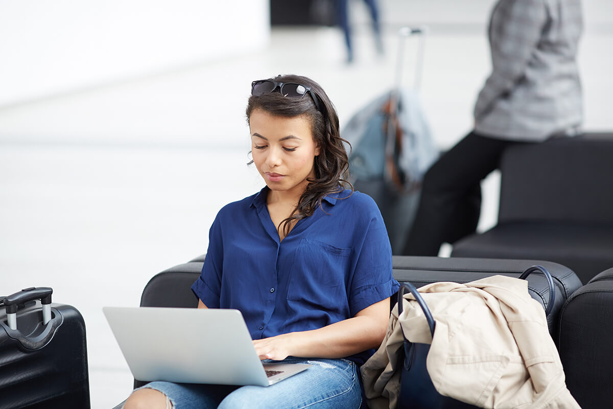 Girl sitting in airport working on a laptop